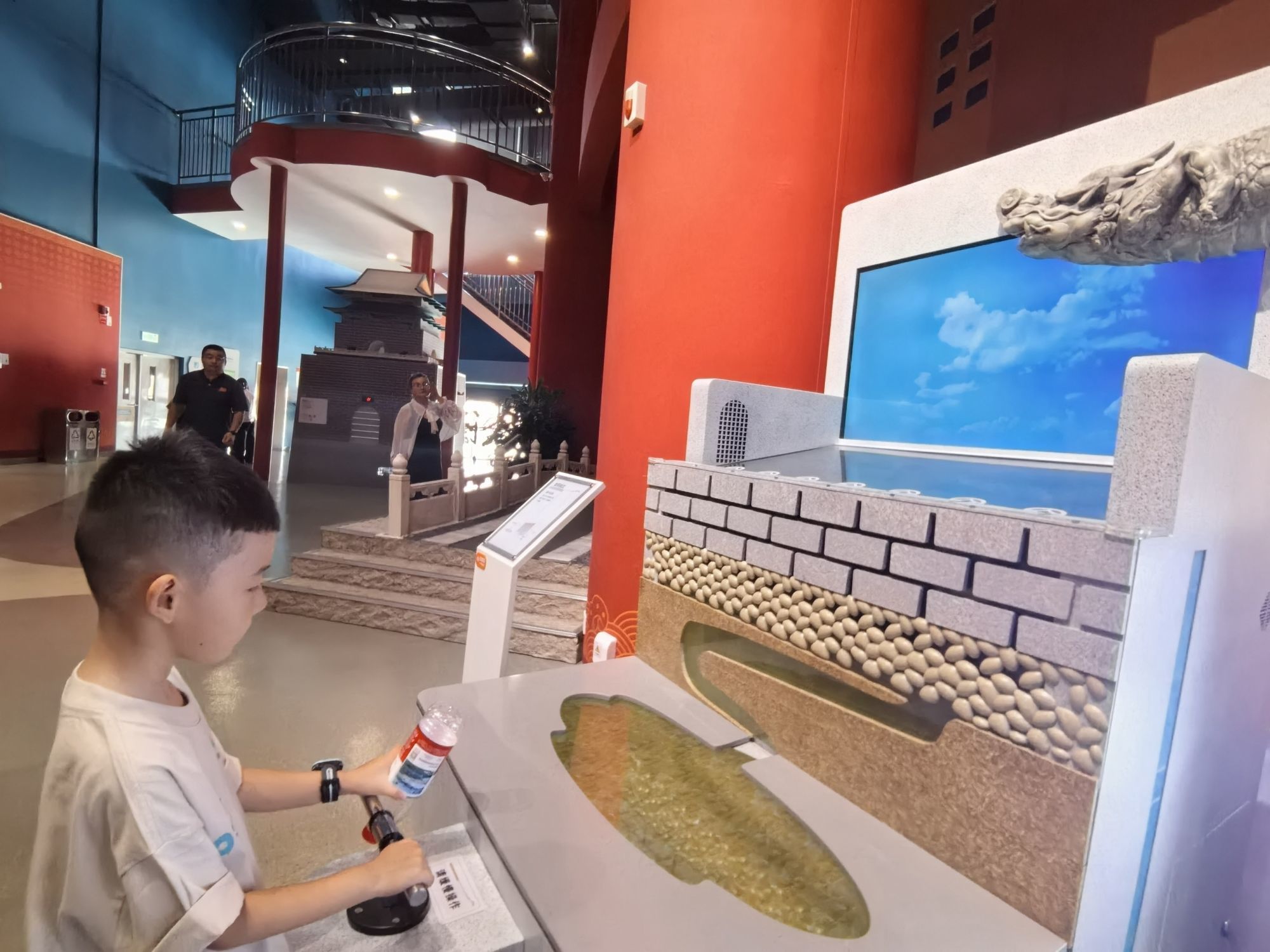 在“科技中轴”展区，小朋友正在体验如何按压出水。