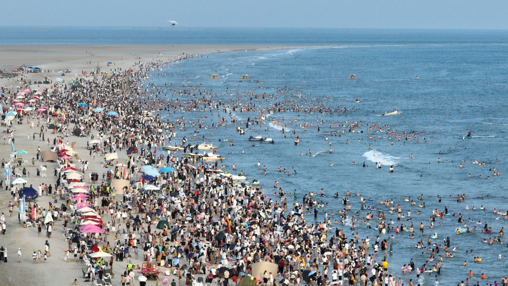 5月4日,游客在广西北海银滩国家旅游度假区戏水(无人机照片)。“五一”假期期间,各地推出丰富多彩的旅游产品供给,加强文旅融合和科技赋能,提升管理水平和服务品质,带动旅游消费欣欣向荣。新华社发(李君光 摄)