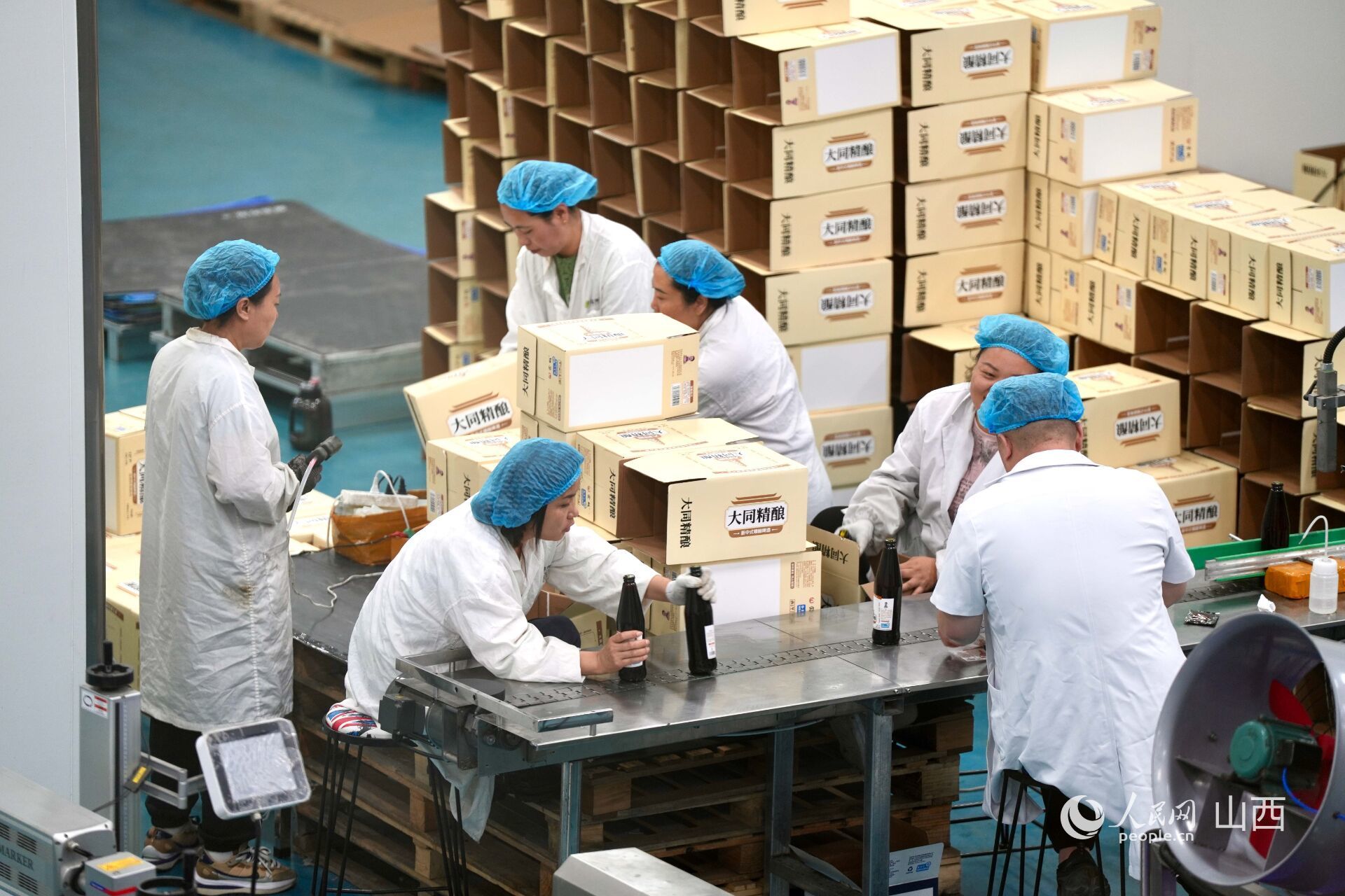 大同三利集团生产车间内,工人正在分装黄花啤酒。人民网 卢鹏宇摄