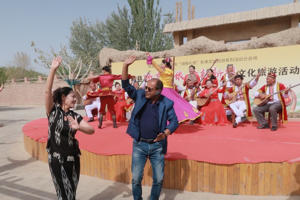 4月26日,外宾在参观阿克苏地区新和县依其艾日克镇加依村时,同表演人员跳舞互动。新华社记者 时艺菲 摄