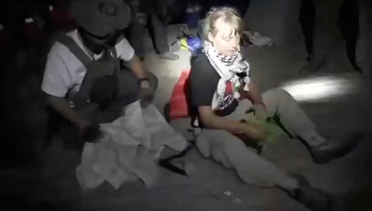 视频截图显示,瑞典环保活动人士格蕾塔·通贝里坐在甲板上,被以军包围。图源:英媒