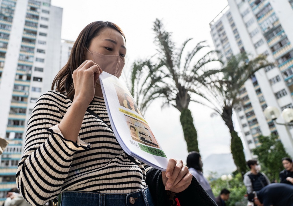 11月27日,香港大埔,宏福苑附近的广福邨公众平台上,一位女士帮助受灾民众分发寻人启事。