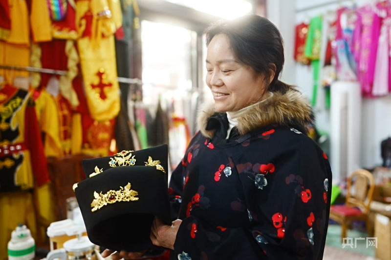 霍瑞婷站在满是社火道具的店铺中，向记者展示社火新产品（央广网记者 张羲轮 摄）