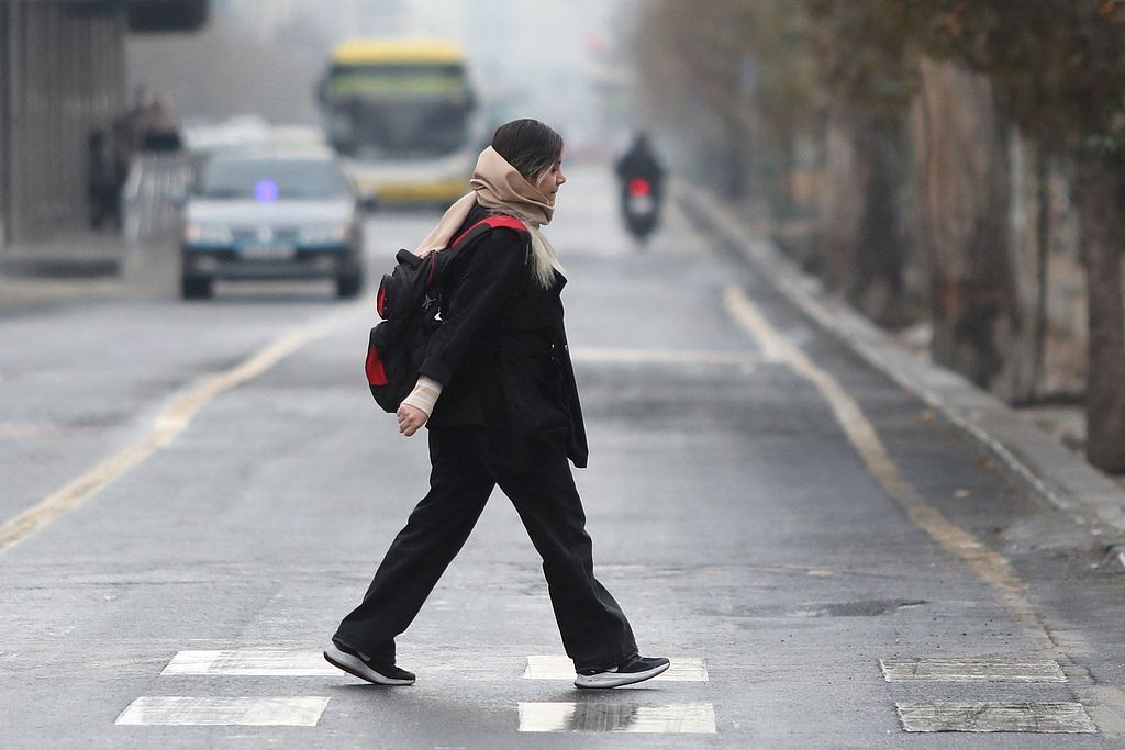 当地时间2025年12月1日,伊朗德黑兰,一名伊朗女子走过斑马线。当天德黑兰迎来冬季首场降雨,此前该市经历了有记录以来最干旱的年份之一。视觉中国 图