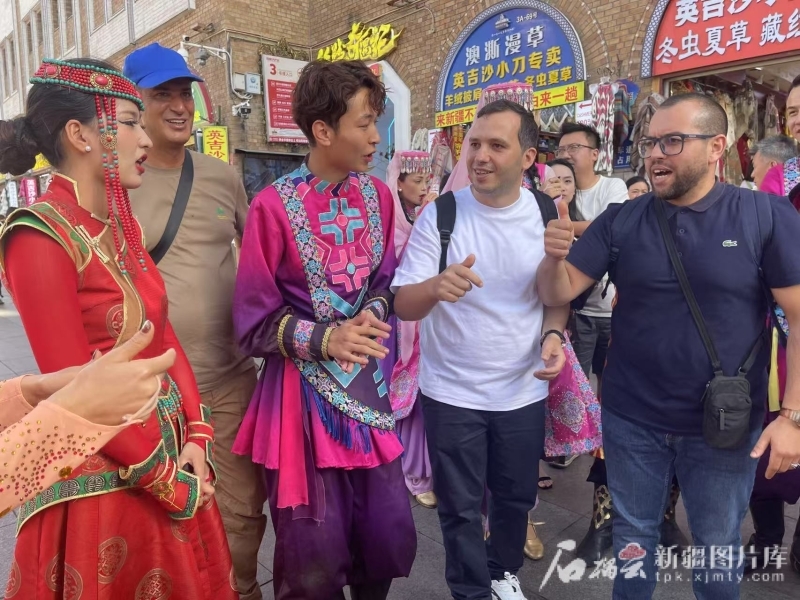 在新疆国际大巴扎,代表团成员与附近一家餐厅演艺人员合影。石榴云/新疆日报记者 任华摄
