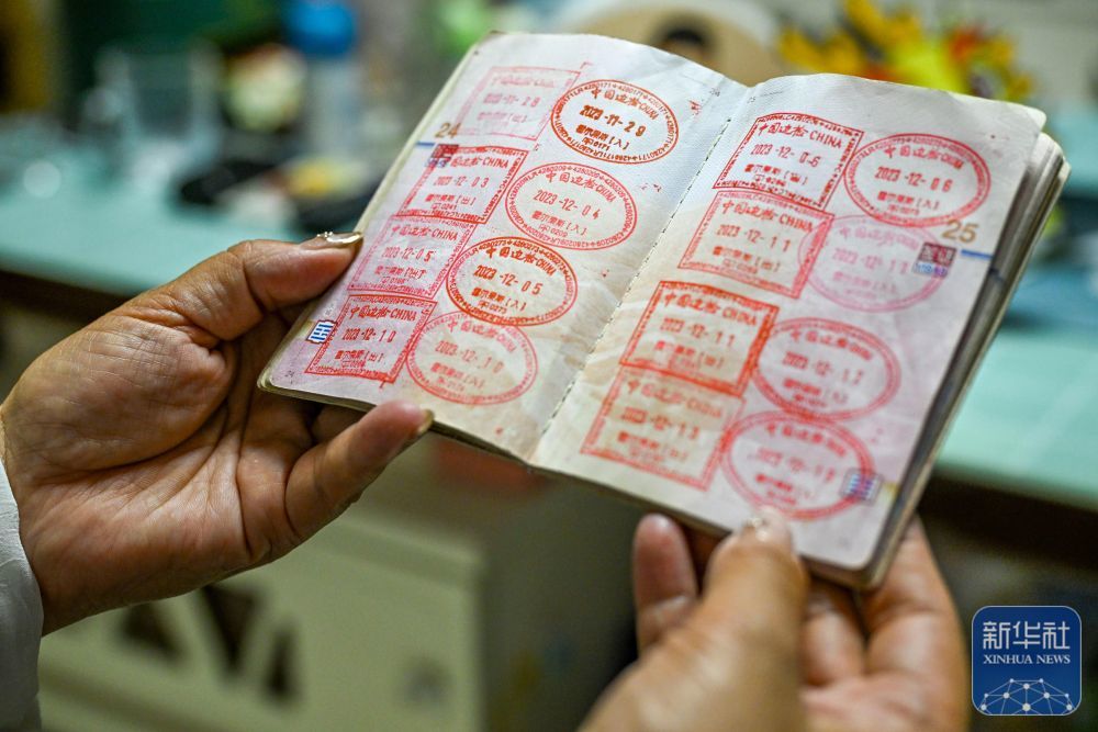 “摆渡人”高云在新疆霍尔果斯的家中展示她的第一本护照(6月9日摄)。这些出入境章记录了她的汽车“摆渡”旅程。