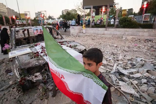 在以色列轰炸后的废墟上,伊朗儿童手举国旗