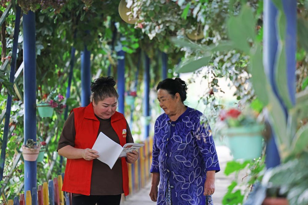 9月18日,达西村村干部买力克木·牙生(左)入户为村民讲解惠民政策。