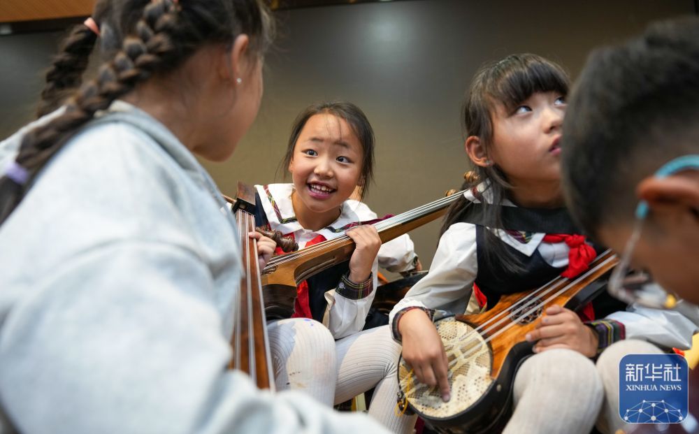 ↑ 9月11日，在拉萨市实验小学，孩子们在弹奏扎念琴间隙交流弹奏技巧。
