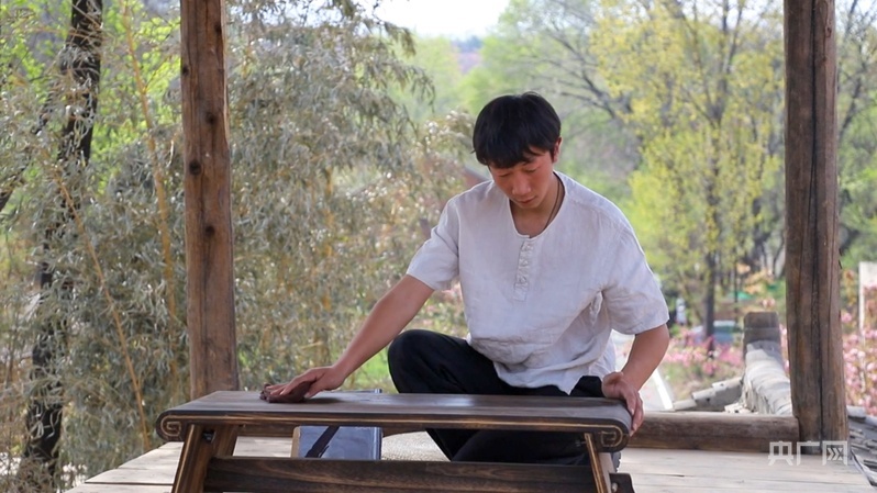 弋龙辉正在自家民宿擦拭琴桌(央广网发 实习记者段懿庭 摄)