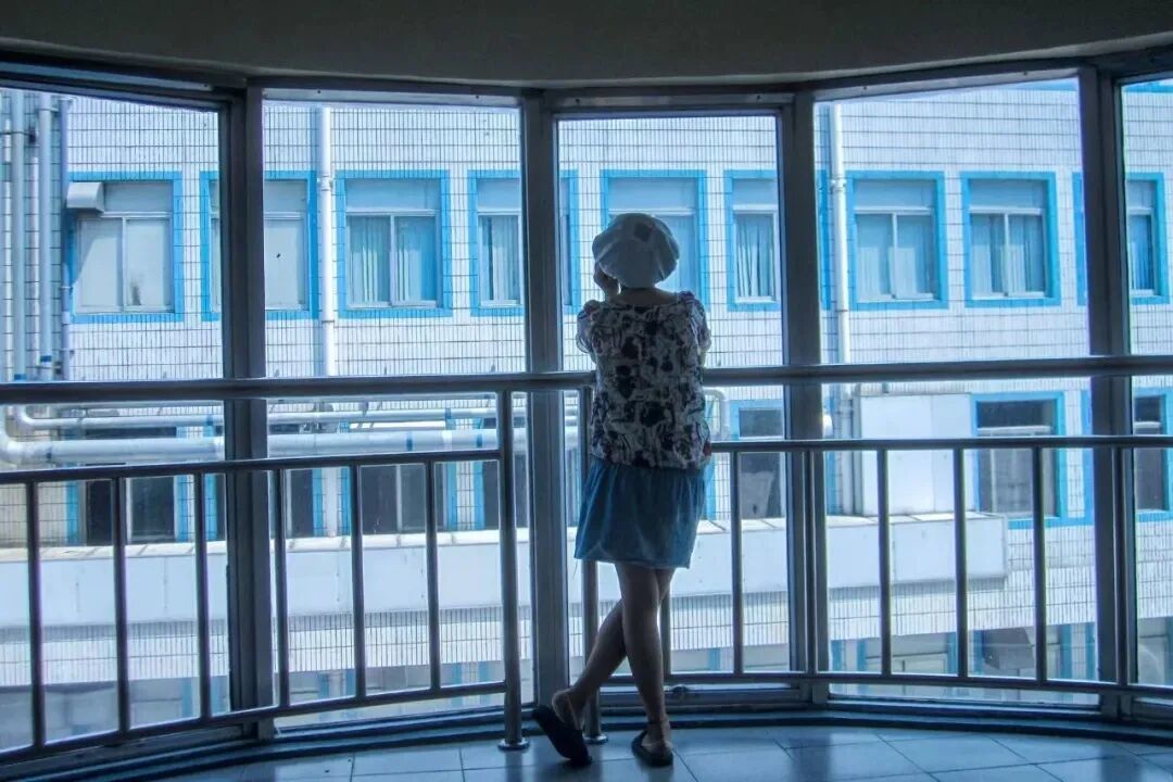 电子厂的女工去洗手间的间隙,站在楼梯间的窗台上发呆。