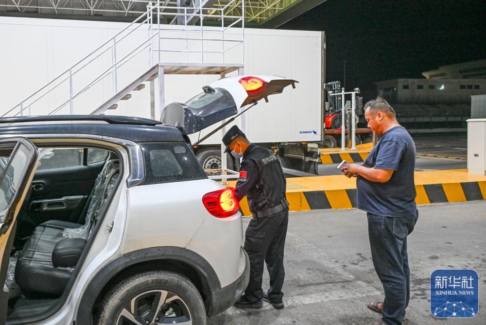 凌晨,在新疆霍尔果斯公路口岸货运执勤现场,霍尔果斯边防检查站移民管理警察查验由“摆渡人”运送出国的车辆(6月11日摄)。