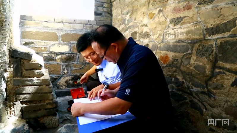 张景龙(左一)与同事利用仪器对丹崖山岩体进行监测(央广网记者 唐磊 摄)