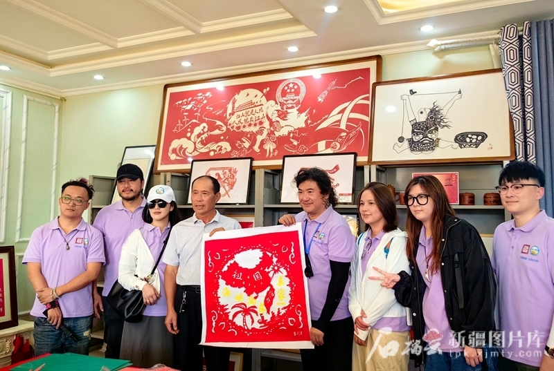 2024年7月11日—16日，台湾青年赴新疆开展两岸青年“互学互鉴、同心同行”新疆交流营活动。在木垒哈萨克自治县英格堡乡月亮地村，两岸青年在展示共同完成的“两岸一家亲”剪纸作品。