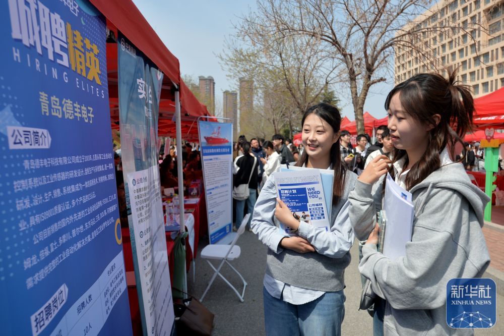 ↑ 4月11日，学生在山东青岛科技大学2025年春季综合类大型双选会招聘活动现场查看企业资料。新华社发（王海滨摄）