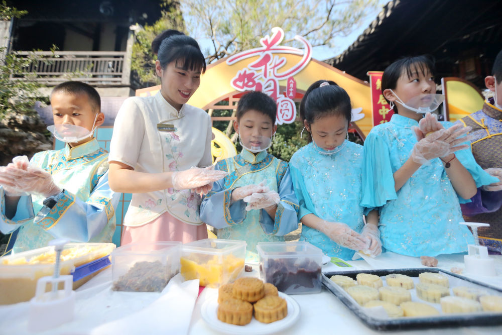 10月6日,在江苏省扬州市何园景区,小朋友们在工作人员的指导下体验制作月饼。新华社发(孟德龙摄)
