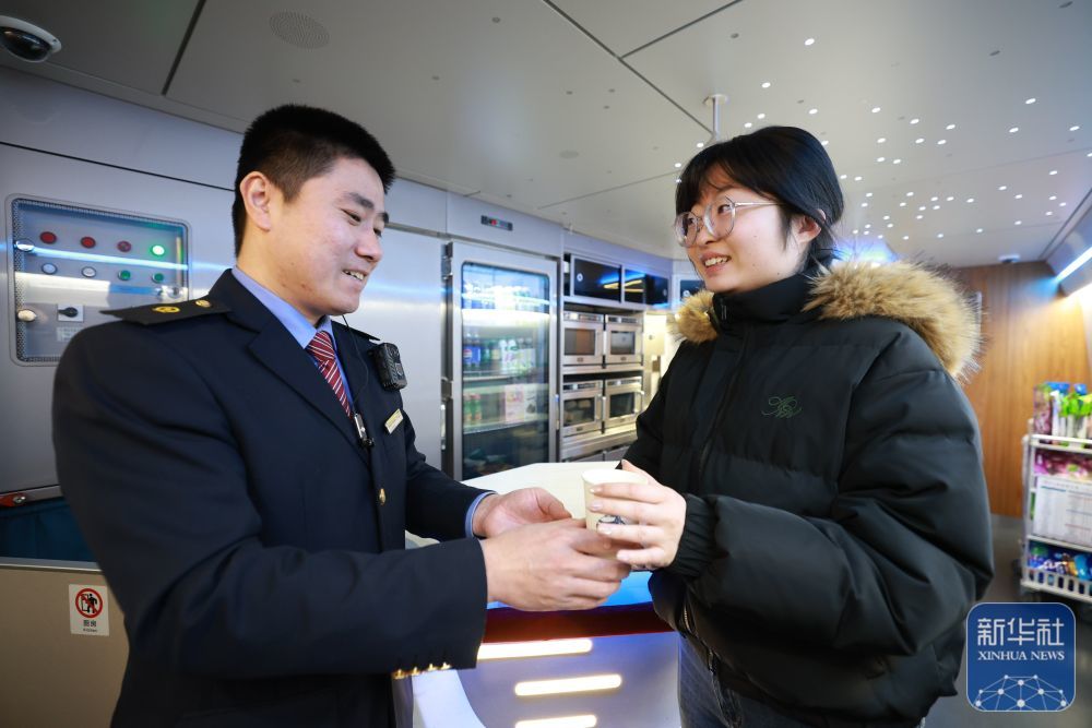↑ 12月11日,在哈尔滨西站,G904次列车工作人员为刚上车的旅客送上热茶。新华社发(徐率摄)