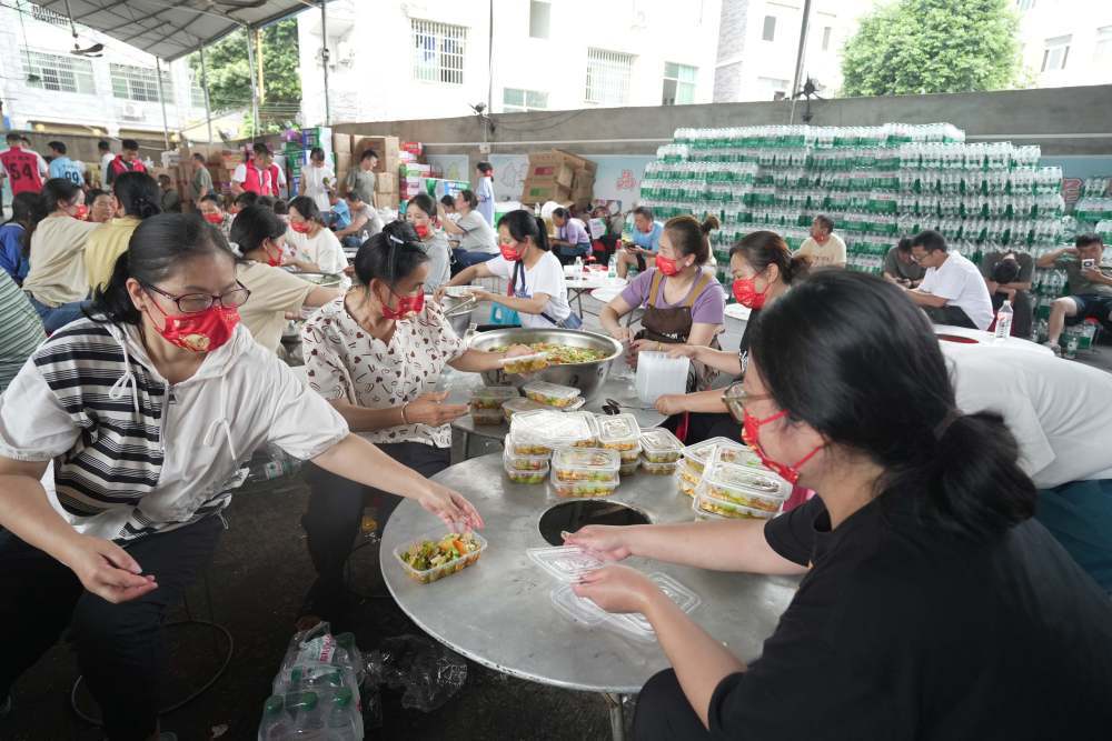 ↑6月26日,村民在忠诚镇一处后勤伙食保障点打包盒饭。