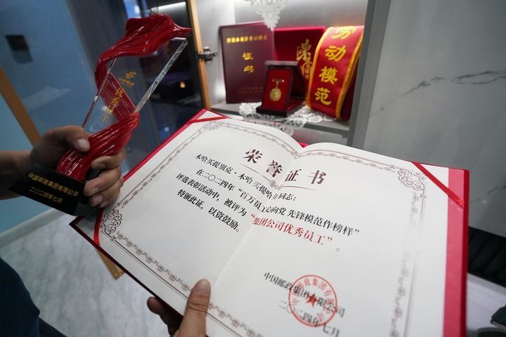 木哈买提别克·木哈买提哈力向记者展示中国邮政集团有限公司颁发给他的“集团公司优秀员工”证书（1月9日摄）。新华每日电讯记者 阿曼 摄