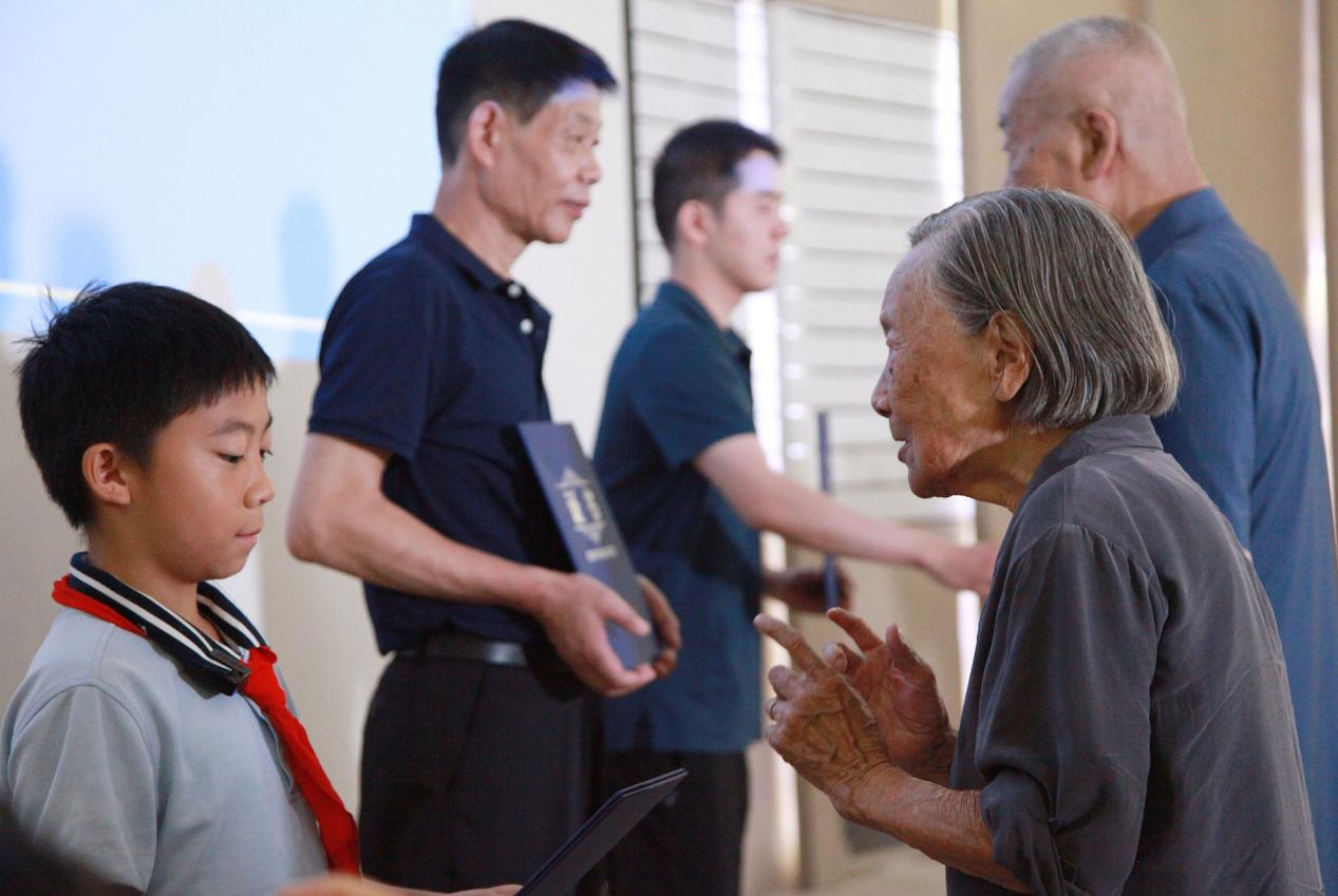 【南京大屠杀幸存者夏淑琴(右前)向曾外孙李玉瀚颁发“南京大屠杀历史记忆传承人”证书 图源:视觉中国】