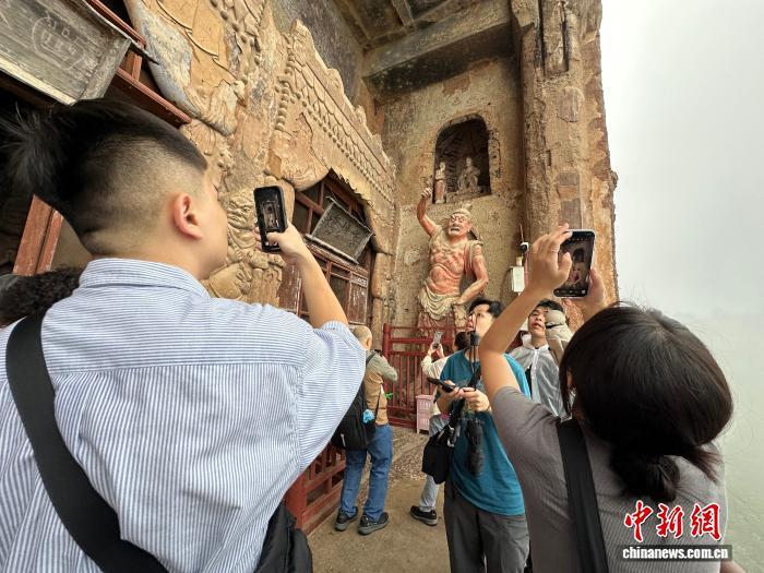 图为台青在麦积山石窟拍照留影 王牧雨 摄