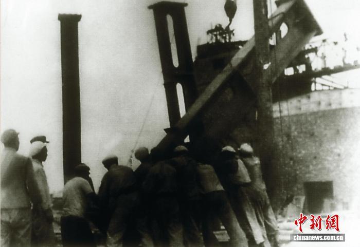 20世纪50年代，新疆八钢建设者靠手工作业，将1.5吨重的钢柱竖在工地上。(八钢公司供图)