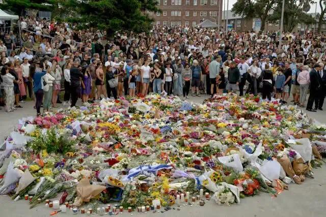 Mourners gather by floral tributes at the Bondi Pavilion in memory of the victims of a shooting at Bondi Beach, in Sydney on Monday.