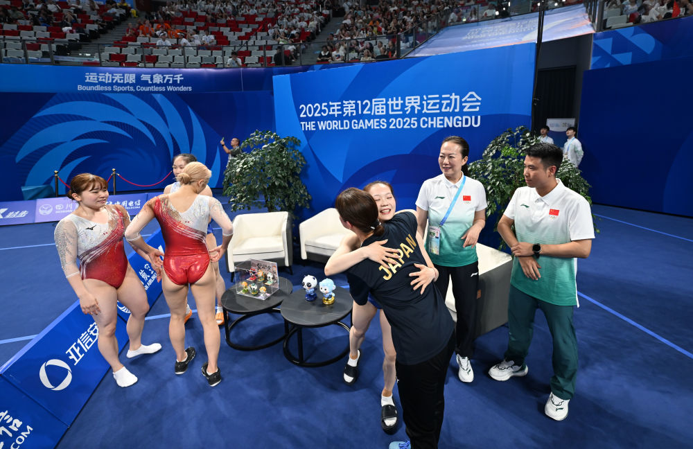 在8月10日举行的2025年成都世运会蹦床女子双人同步决赛后,日本队教练与中国队选手胡译乘拥抱祝贺夺冠。