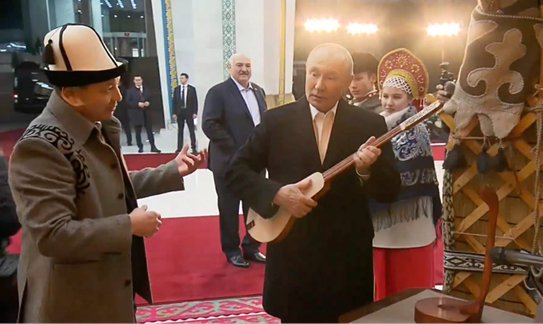 当地时间26日,普京访问吉尔吉斯斯坦期间弹奏库姆孜,卢卡申科在身后聆听。图自俄媒