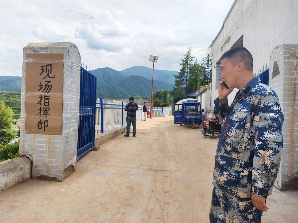8月10日,王栋(右一)正在现场指挥部前联系工作。新华社记者 崔翰超 摄