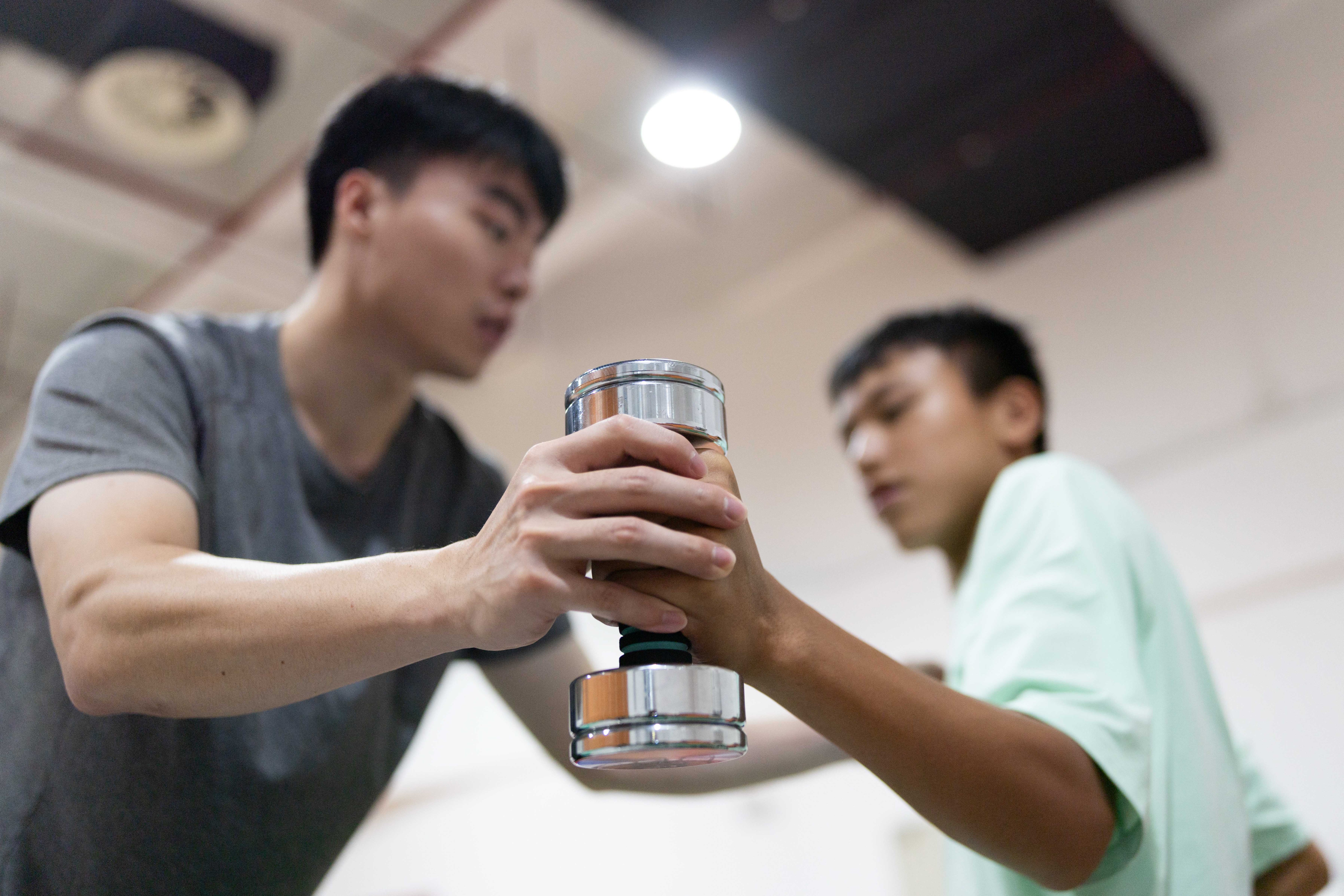 在结束早午两操后，助教林琪深单独留下钟英杰，帮助他用哑铃加练手臂伸展力量。