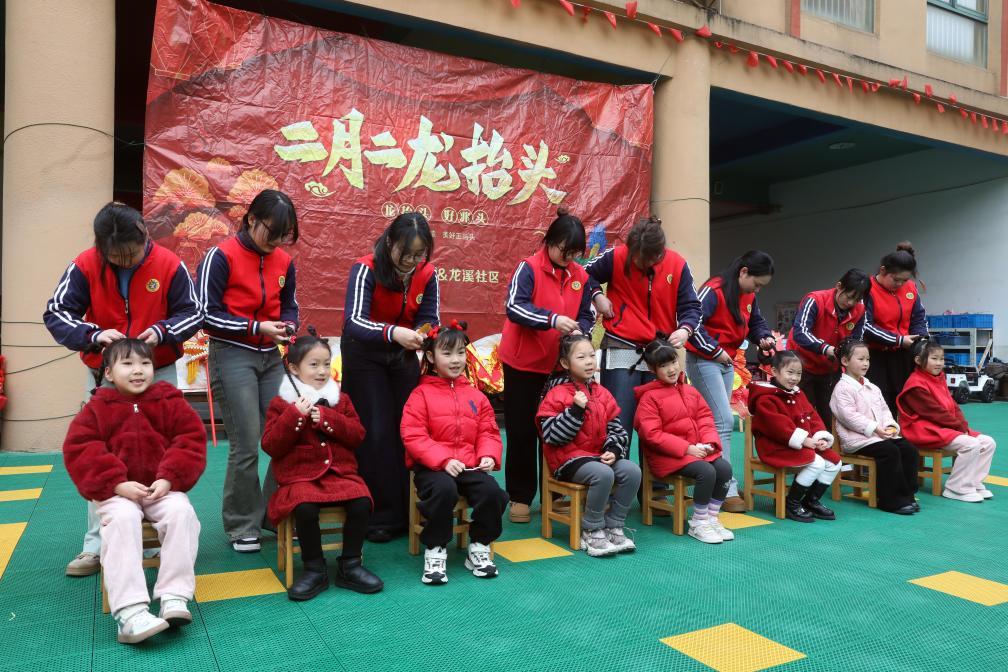 2月27日，江苏省宜兴市均陶幼儿园的老师为孩子们“梳龙头”“扎龙辫”。新华社发（丁焕新摄）