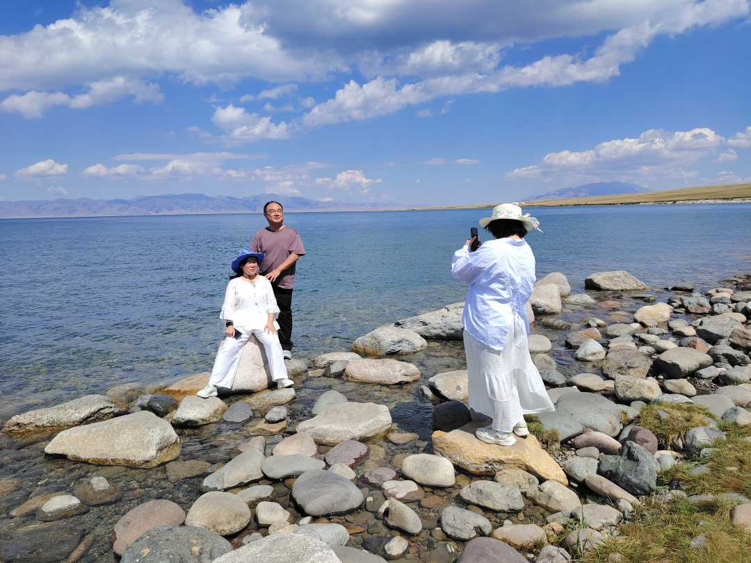 游客在赛里木湖湖边拍照。刘沛恺摄