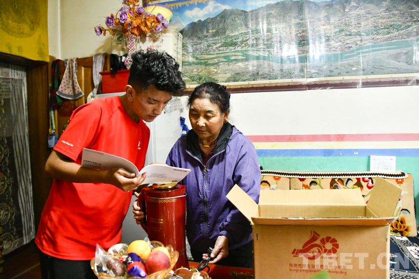 图为卓嘎与儿子罗布次仁一起仔细研究这一台全自动酥油茶壶的使用 摄影:赵振宇