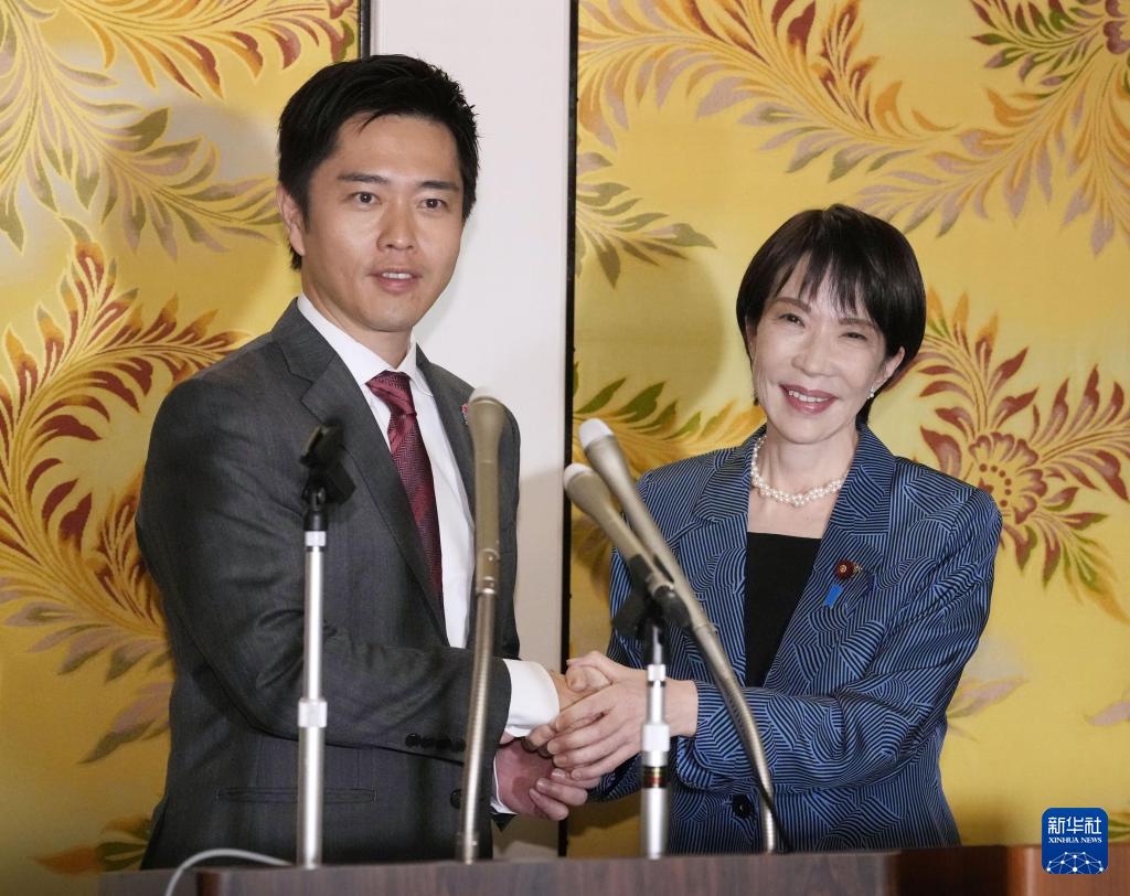 高市早苗(右)与维新会党首吉村洋文在记者会上握手。图源:新华社