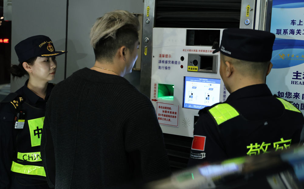 12月23日,“粤车南下”入境香港市区的首位通关车主彭先生(中)在“一站式”通道办理通关手续。新华社记者 黄国保 摄
