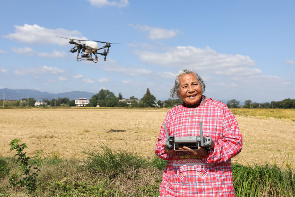 2025年10月23日,在安徽省桐城市新渡镇老梅村,82岁奶奶戴淑英与植保无人机合影。新华社记者 杜潇逸 摄
