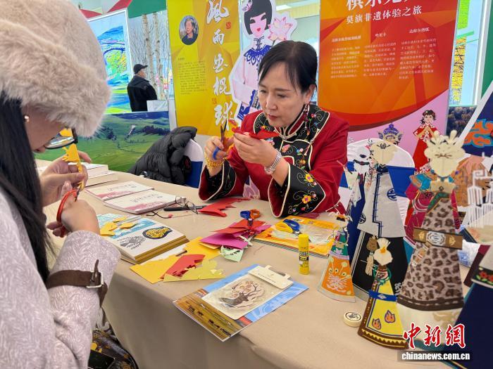图为达斡尔族“哈尼卡”剪纸老师现场教授游客剪纸技艺。　中新网记者 张玮 摄