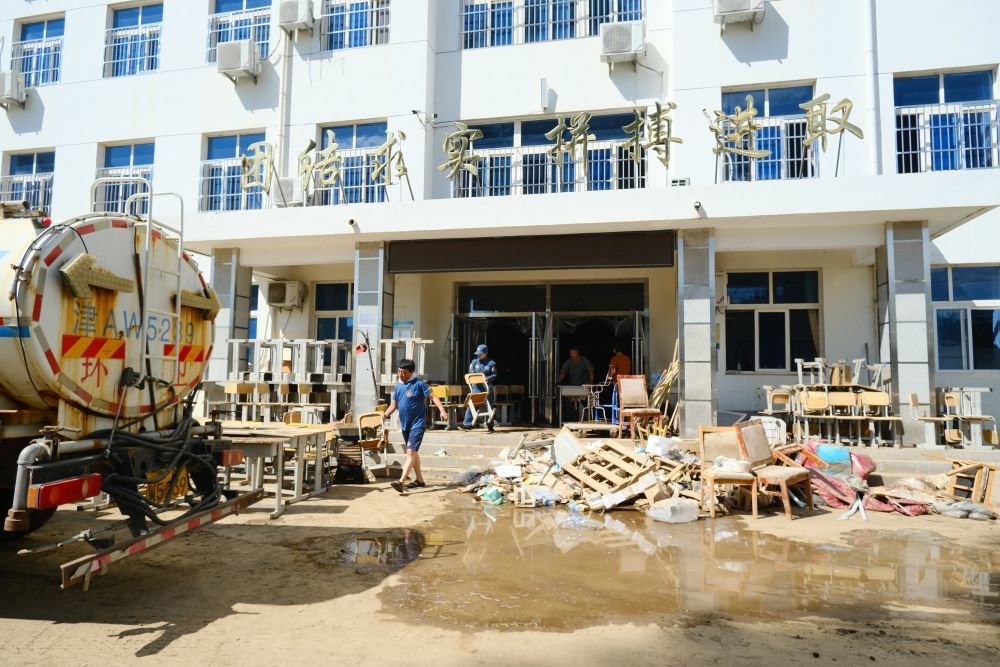 蓝天救援队的队员正在下营中学帮助清理。新华社记者 张宇琪 摄