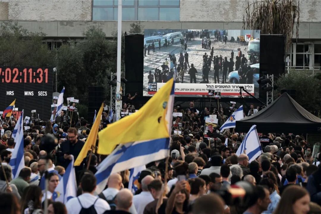 10月13日,在以色列特拉维夫,人们通过大屏幕观看被哈马斯扣押人员释放直播。图/新华