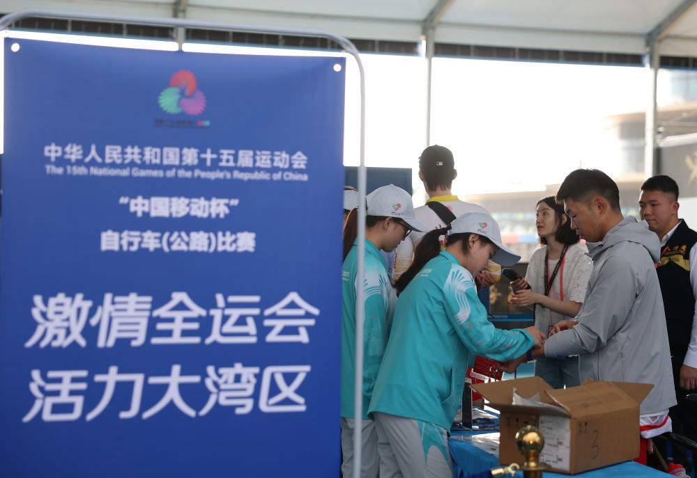 11月8日,志愿者为第十五届全国运动会公路自行车男子个人赛决赛参赛人员佩戴通关手环。 新华社记者 张晨霖 摄