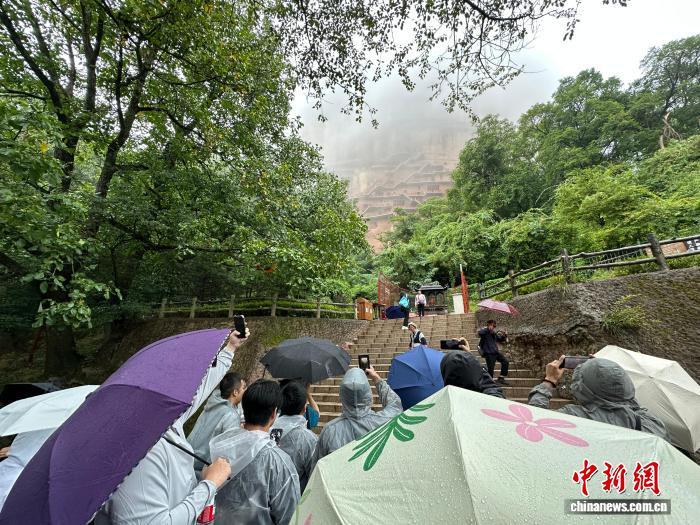 图为台青在麦积山石窟下观景台拍摄烟雨中的麦积山石窟 王牧雨 摄