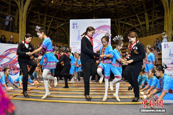2024年10月27日，海南省五指山市，法国巴黎宝丽声童声合唱团与海南五指山黎苗童声合唱团成员一起体验竹竿舞。中新社记者 骆云飞 摄