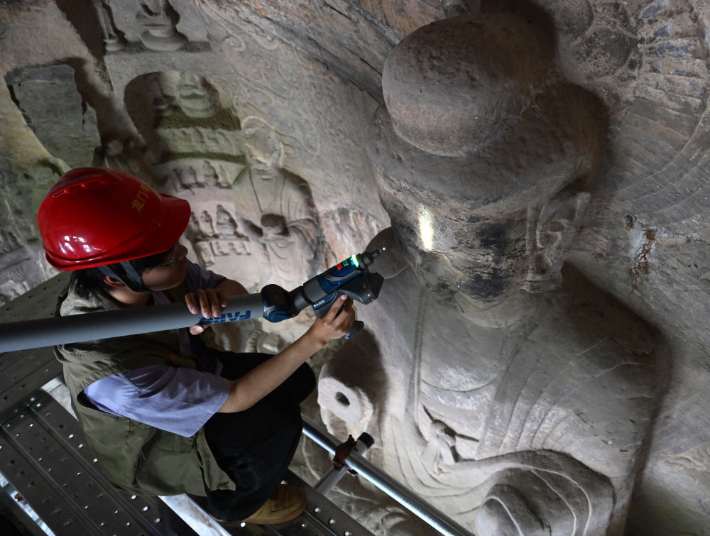4月9日，武汉大学文化遗产智能计算实验室团队成员在魏字洞使用关节臂扫描仪对佛像进行数字化扫描。
