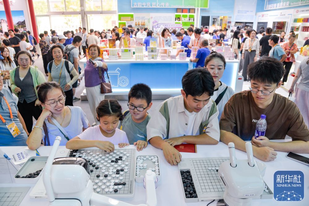 ↑ 9月13日,在北京首钢园,参展者在2025年服贸会文旅服务展馆经开区展台与“元萝卜”AI下棋机器人互动。