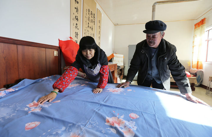 甘肃省定西市安定区内官营镇先锋村村民在整理刚领到的新床单(2025年11月19日摄)。初冬时节,当地开展“问暖”“送暖”“助暖”活动,保障困难群众温暖过冬。新华社发(王克贤摄)