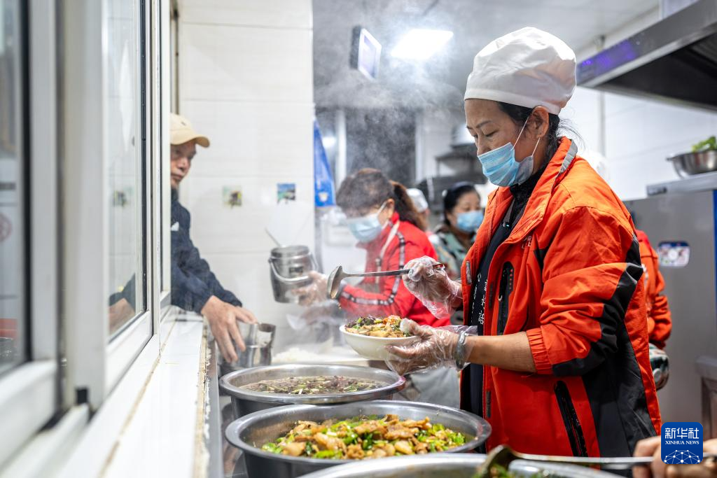 在昆明市幸福家园小区爱心食堂,王兰兰给来吃午饭的老人盛菜(5月28日摄)。