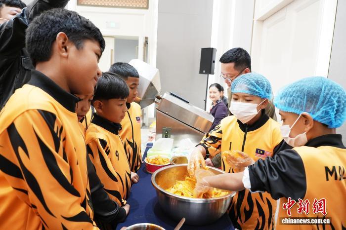 12月12日晚,“侨心同源 足连四海”安源红色小健将中外青少年足球嘉年华暨华侨华裔联谊交流活动现场,国外青少年排队试吃辣条。李小涛 摄