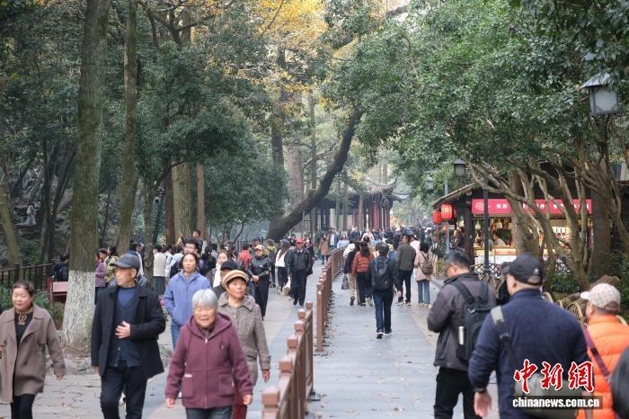 12月1日，游客行走在杭州灵隐飞来峰景区内。中新社记者　曹丹　摄