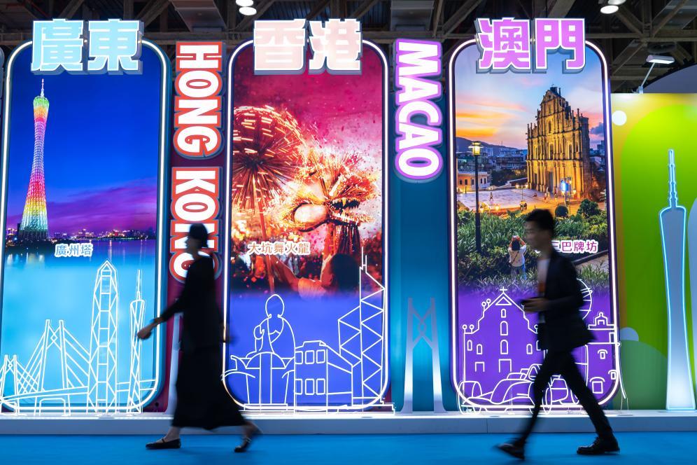 4月25日，参观者从第十三届澳门国际旅游（产业）博览会大湾区展板前经过。新华社发（张金加摄）
